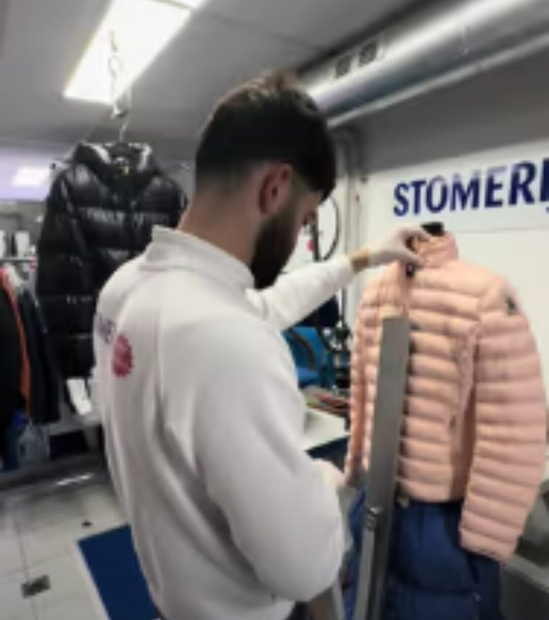 Medewerker brengt een donsjas in model op de strijkpop