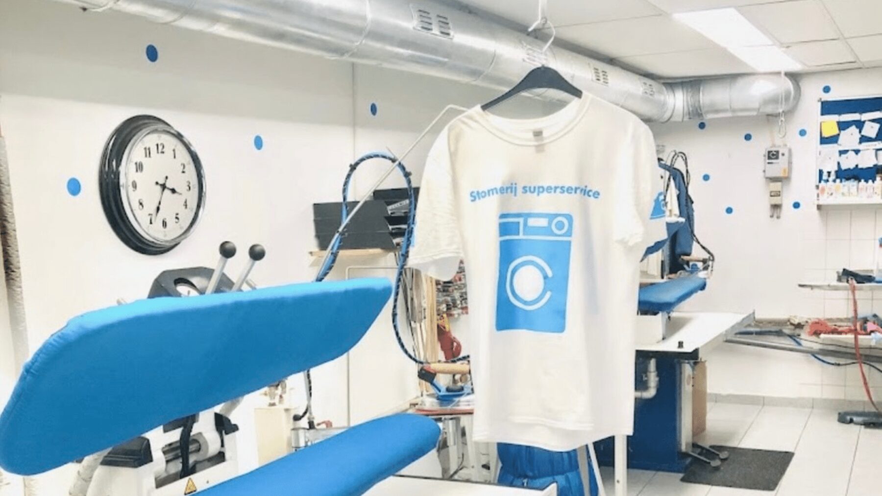 De werkplaats van Stomerij Superservice met strijktafels en een shirt met het eigen logo